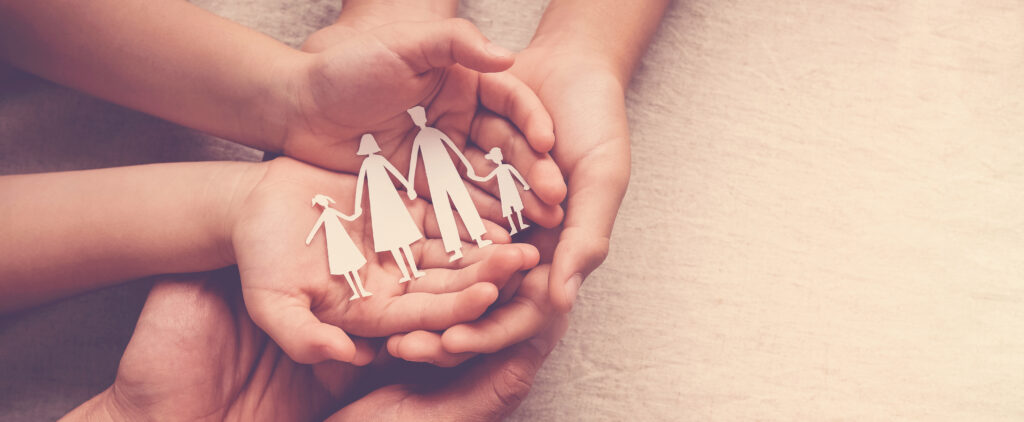 Hands holding a paper cutout family, symbolizing care and togetherness